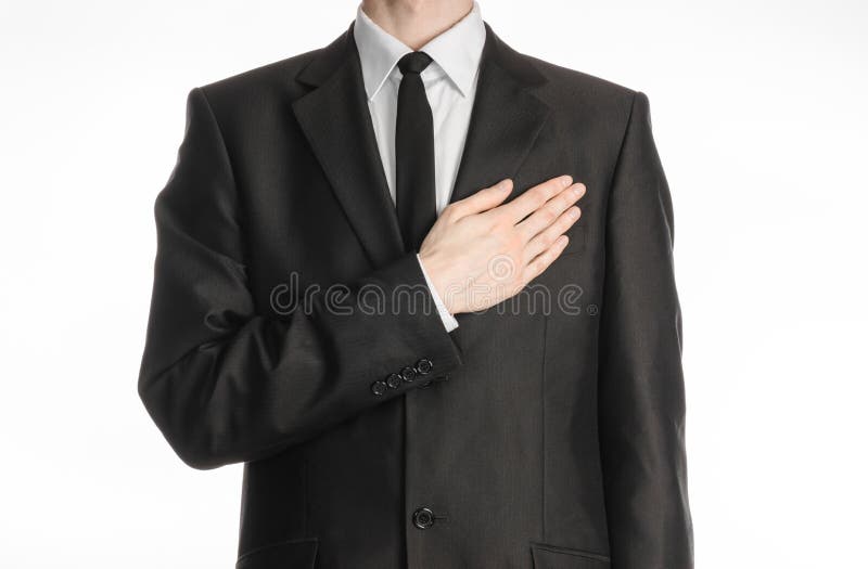 Homme d'affaires et sujet de geste : un homme dans un costume noir avec un lien a mis sa main sur son coffre d'isolement sur le f image stock Homme d'affaires et sujet de geste : un homme dans un costume noir avec un lien a mis sa main sur son coffre d'isolement sur le f image stock