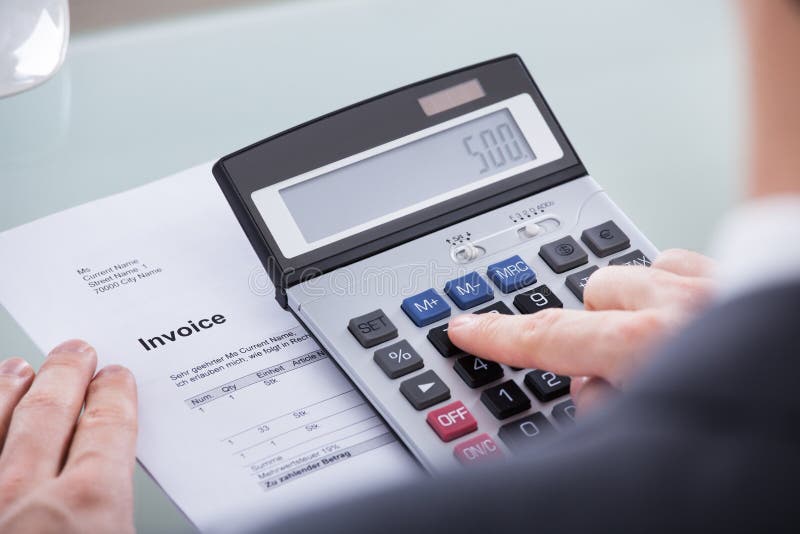 Close-up Of Businessperson Doing Calculation On Calculator With Document. Close-up Of Businessperson Doing Calculation On Calculator With Document