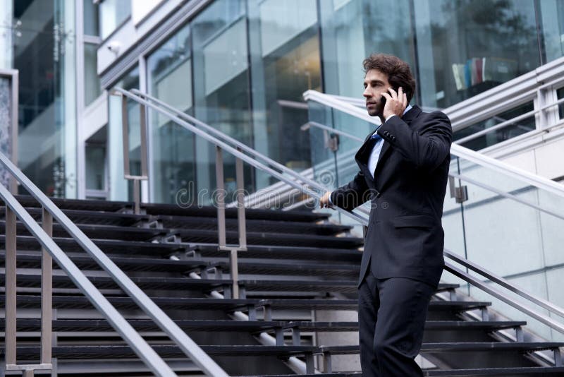 Homme d'affaires fier au téléphone devant son bureau image stock Homme d'affaires fier au téléphone devant son bureau image stock