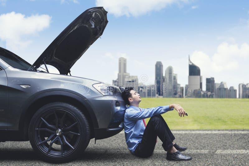Homme d'affaires frustrant se penchant sur la voiture décomposée photos libres de droits Homme d'affaires frustrant se penchant sur la voiture décomposée photos libres de droits