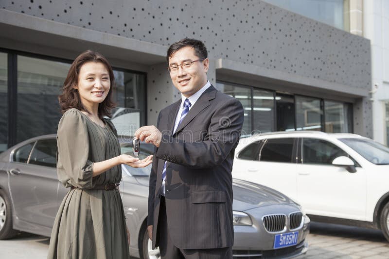 Homme d'affaires Handing Car Keys à la femme dans l'atelier de réparations automatiques photographie stock libre de droits Homme d'affaires Handing Car Keys à la femme dans l'atelier de réparations automatiques photographie stock libre de droits