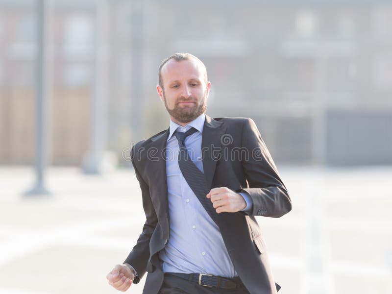 Homme d'affaires heureux courant dans la ville image stock Homme d'affaires heureux courant dans la ville image stock