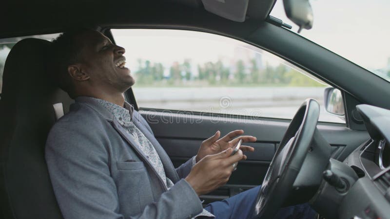 Homme d'affaires heureux d'afro-américain surfant le media social sur sa tablette se reposant à l'intérieur de sa voiture banque de vidéos