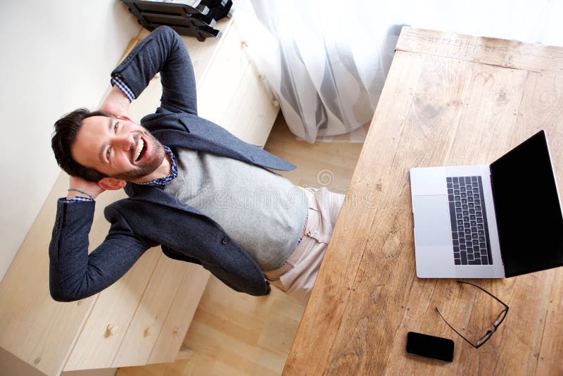 Homme d'affaires heureux détendant dans le bureau avec l'ordinateur portable