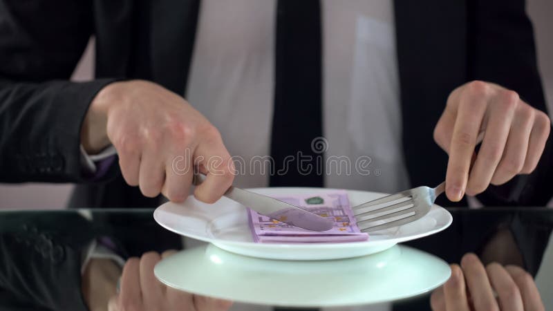Homme d'affaires mangeant d'euro billets de banque, gaspillant le concept, détournement de budget photographie stock libre de droits Homme d'affaires mangeant d'euro billets de banque, gaspillant le concept, détournement de budget photographie stock libre de droits