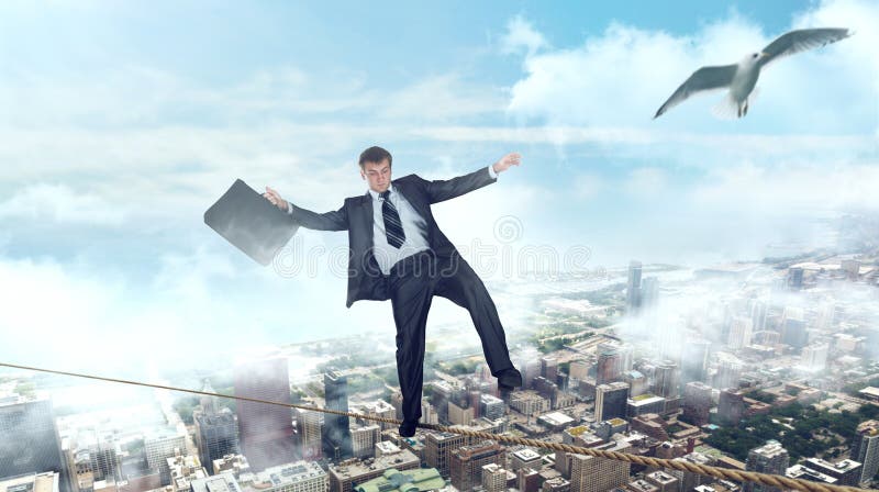 Homme d'affaires marchant sur une corde sur le centre d'affaires photographie stock libre de droits Homme d'affaires marchant sur une corde sur le centre d'affaires photographie stock libre de droits