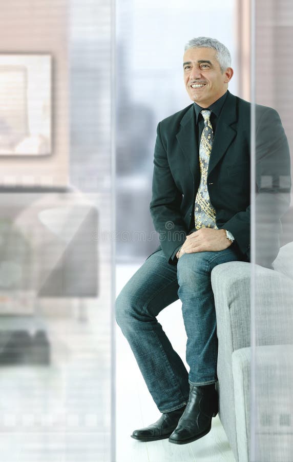 Casual businessman sitting on couch in modern office, smiling. Casual businessman sitting on couch in modern office, smiling.