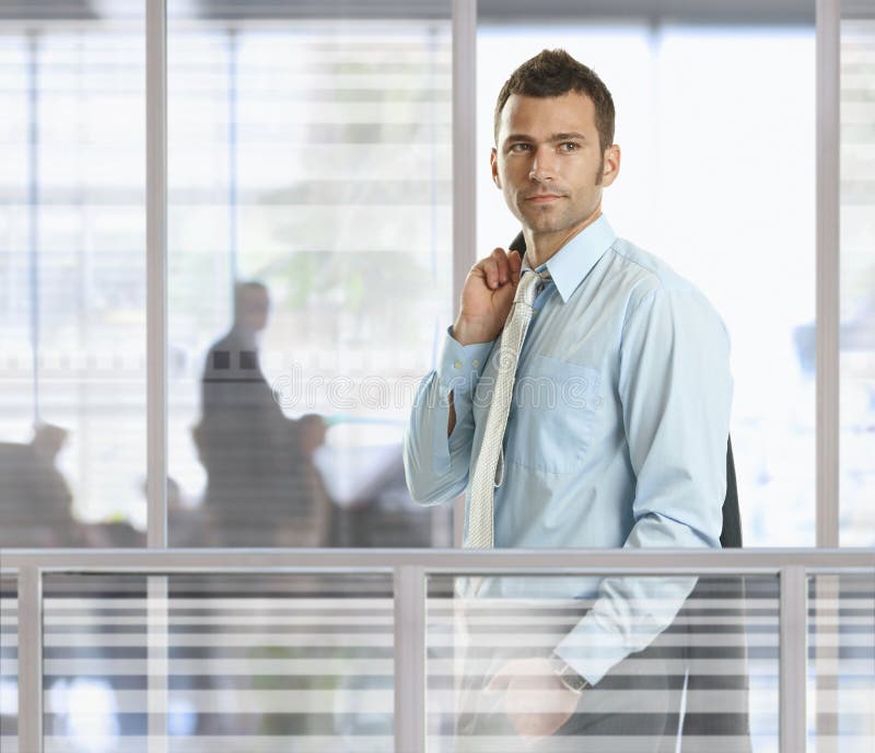 Casual businessman standing in front of glass walls in office, smiling. Casual businessman standing in front of glass walls in office, smiling.