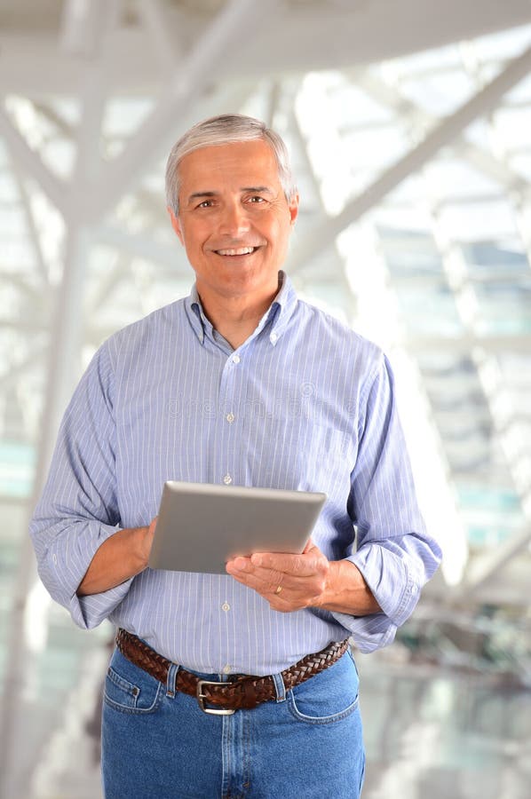 Closeup of a casual businessman in a modern factory holding a tablet computer. Vertical Format. Closeup of a casual businessman in a modern factory holding a tablet computer. Vertical Format.