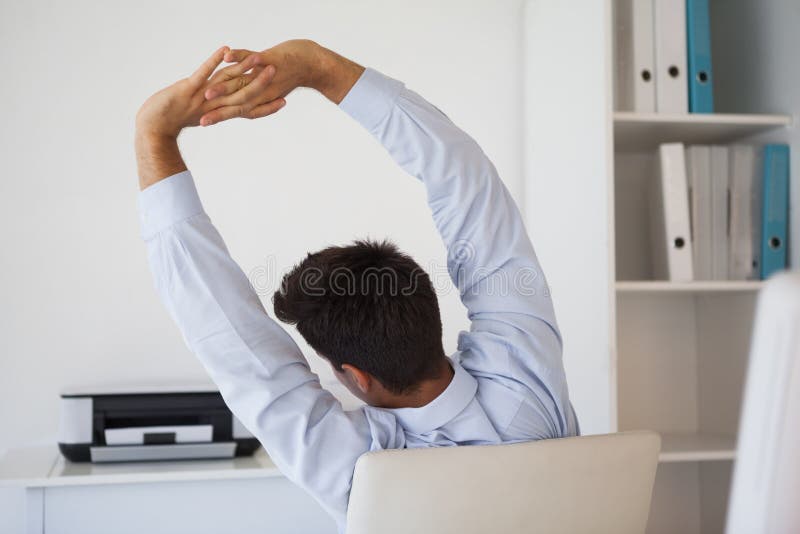 Casual businessman stretching in swivel chair in his office. Casual businessman stretching in swivel chair in his office