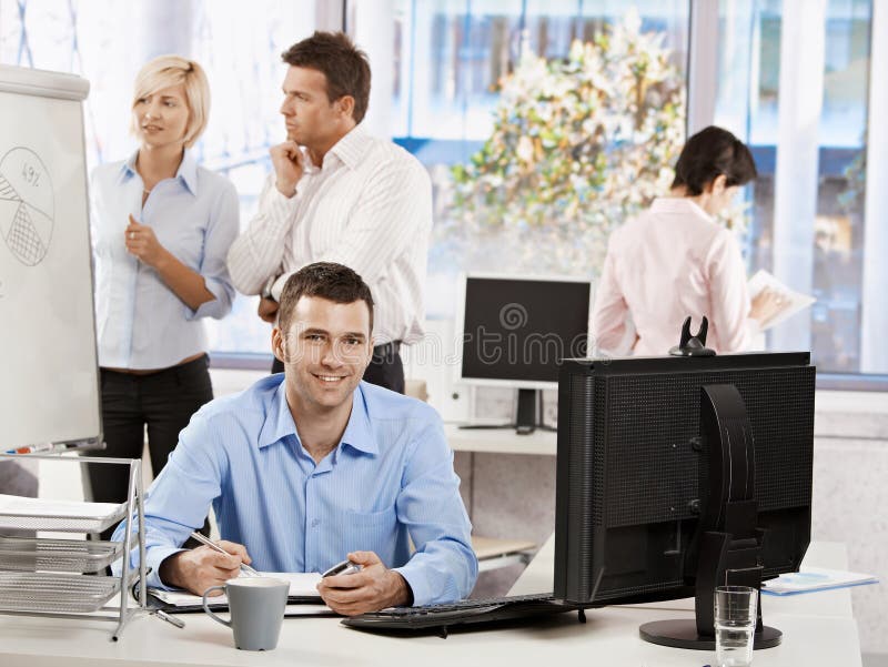 Casual businessman working in office, sitting at desk, writing notes to personal organizer. Casual businessman working in office, sitting at desk, writing notes to personal organizer.