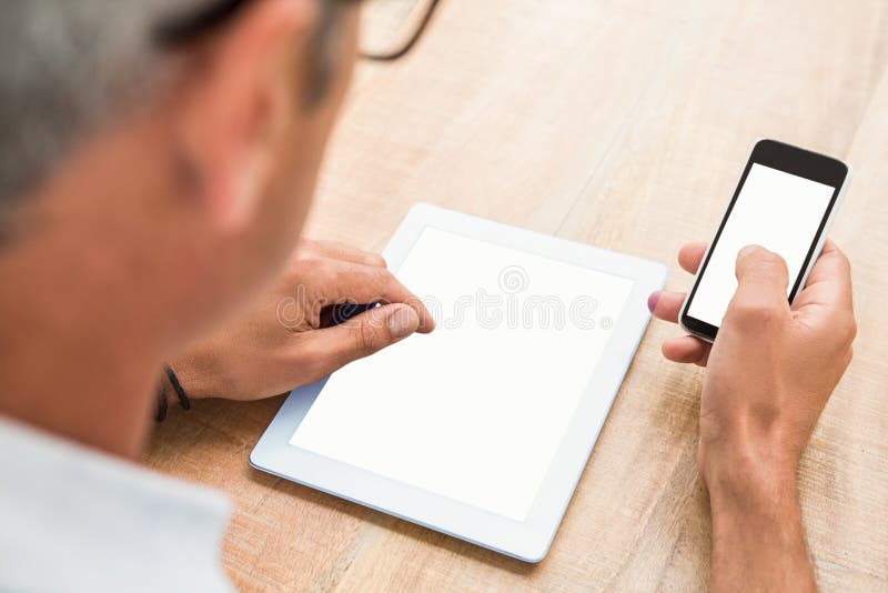 Casual businessman using smartphone and tablet on wooden desk. Casual businessman using smartphone and tablet on wooden desk