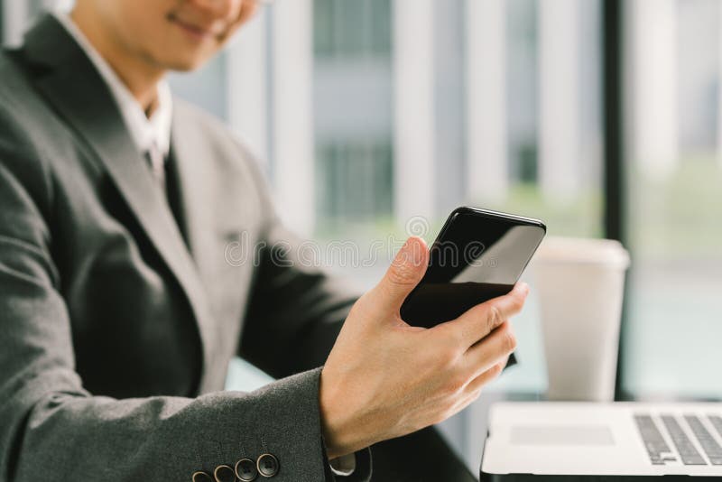 Homme d'affaires ou entrepreneur asiatique à l'aide du smartphone et de l'ordinateur portable, fonctionnant dans le bureau modern photo libre de droits Homme d'affaires ou entrepreneur asiatique à l'aide du smartphone et de l'ordinateur portable, fonctionnant dans le bureau modern photo libre de droits