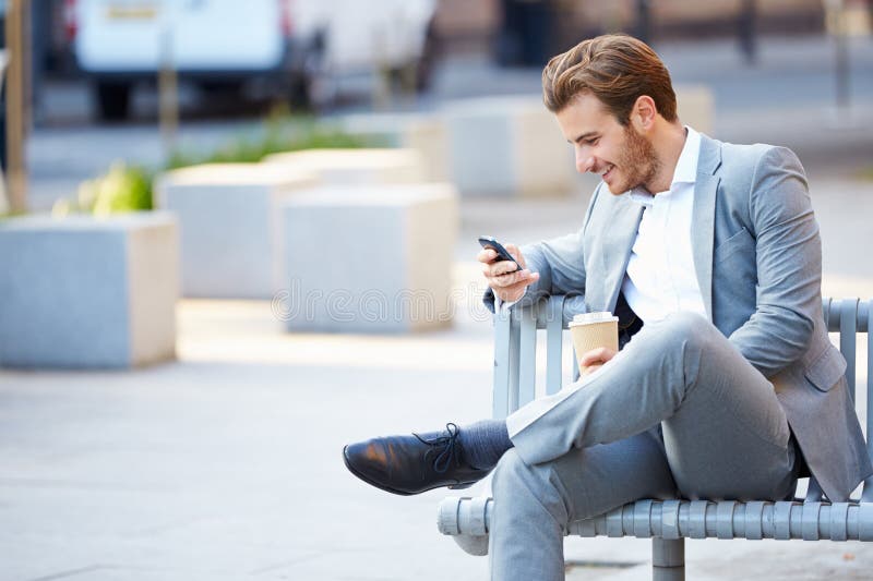 Homme d'affaires On Park Bench avec du café utilisant le téléphone portable