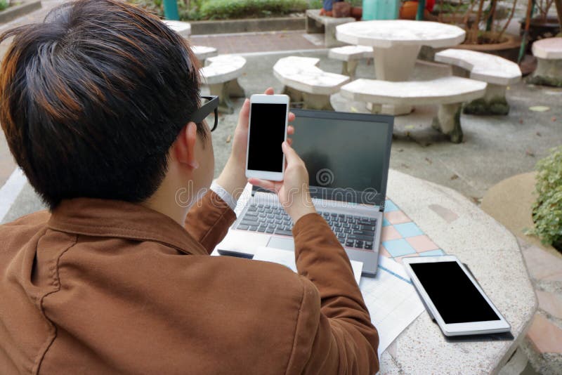 Homme d'affaires s'asseyant sur la chaise de marbre et lisant un message sur son smartphone mobile en parc photo libre de droits Homme d'affaires s'asseyant sur la chaise de marbre et lisant un message sur son smartphone mobile en parc photo libre de droits