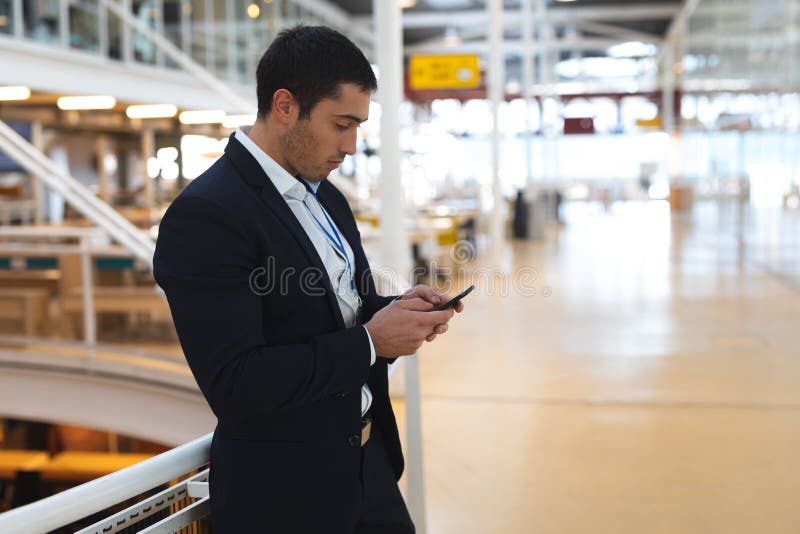 Homme d'affaires se penchant sur la balustrade et à l'aide du téléphone portable dans un bureau moderne images stock Homme d'affaires se penchant sur la balustrade et à l'aide du téléphone portable dans un bureau moderne images stock