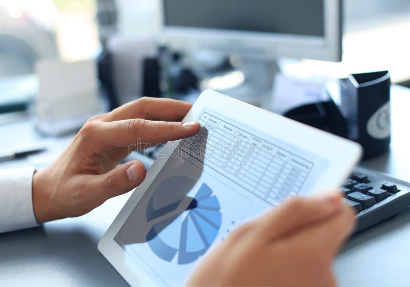 Business person analyzing financial statistics displayed on the tablet screen. Business person analyzing financial statistics displayed on the tablet screen