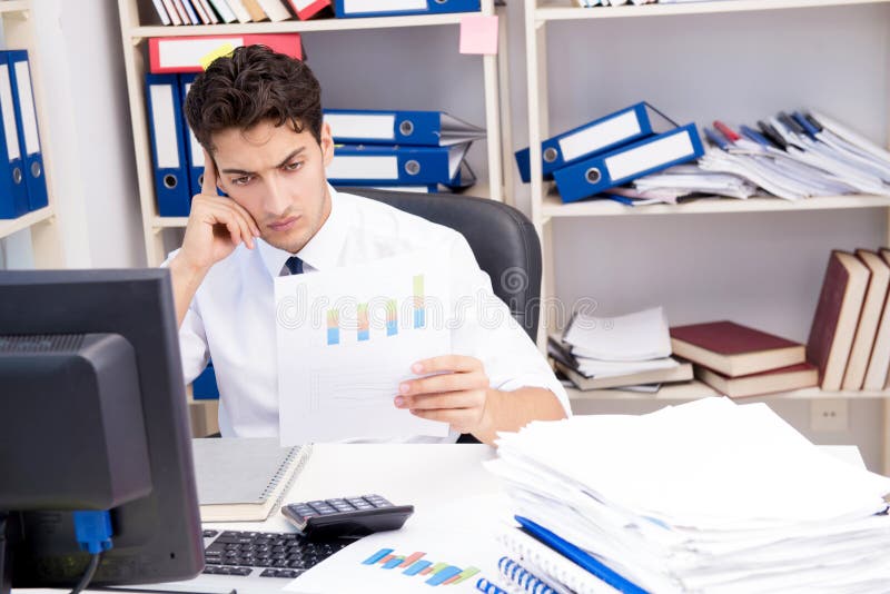 Homme d'affaires travaillant dans le bureau avec des piles des livres et des papiers photographie stock libre de droits Homme d'affaires travaillant dans le bureau avec des piles des livres et des papiers photographie stock libre de droits