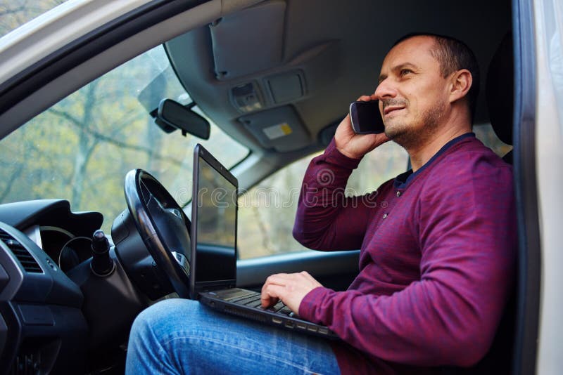 Homme d'affaires travaillant sur un ordinateur portable dans la voiture photographie stock libre de droits Homme d'affaires travaillant sur un ordinateur portable dans la voiture photographie stock libre de droits