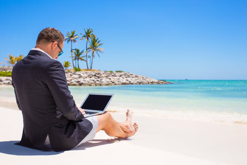 Homme d'affaires utilisant l'ordinateur portable sur la plage tropicale