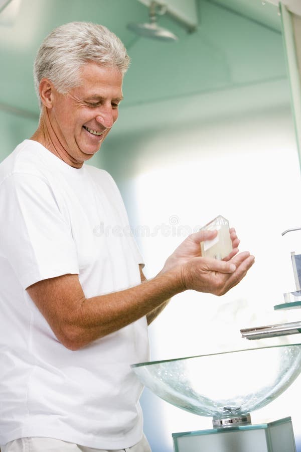 Homme dans la salle de bains appliquant la lotion après-rasage photo stock Homme dans la salle de bains appliquant la lotion après-rasage photo stock