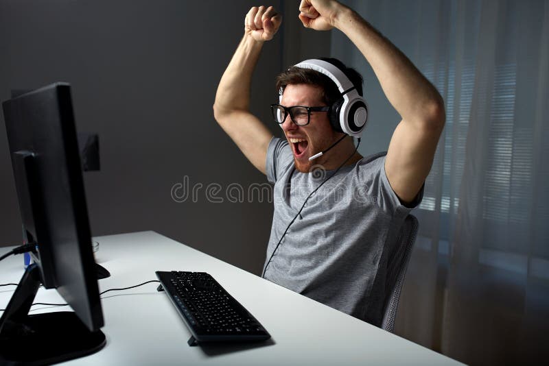 Homme dans le casque jouant le jeu vidéo d'ordinateur à la maison photo libre de droits Homme dans le casque jouant le jeu vidéo d'ordinateur à la maison photo libre de droits