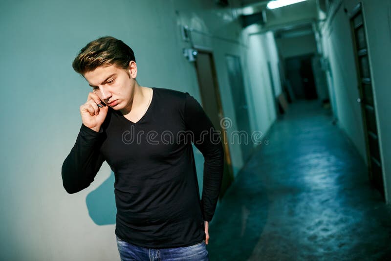 Homme dans le couloir sombre avec le contre-jour parlant au téléphone, marché hors de la salle de bureau Conversation sérieuse images stock Homme dans le couloir sombre avec le contre-jour parlant au téléphone, marché hors de la salle de bureau Conversation sérieuse images stock
