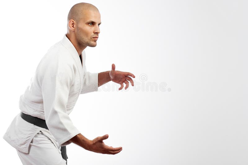 Homme dans le kimono blanc posant sur le fond blanc photographie stock Homme dans le kimono blanc posant sur le fond blanc photographie stock