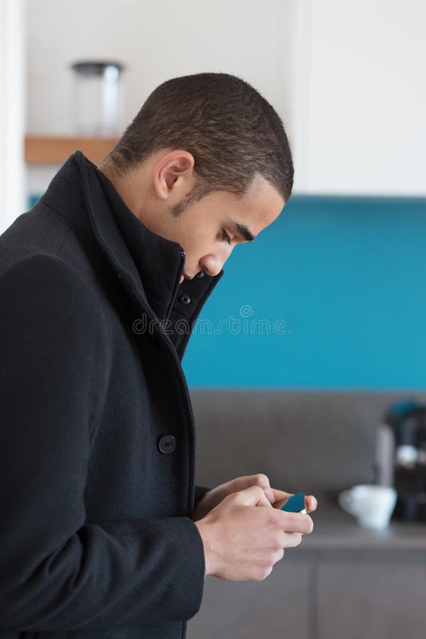 Homme dans le manteau noir regardant le téléphone portable photographie stock libre de droits Homme dans le manteau noir regardant le téléphone portable photographie stock libre de droits