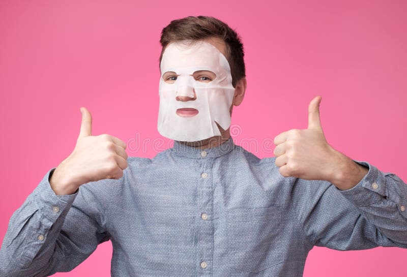 Homme dans un masque cosmétique pour le pouce d'apparence de soins de la peau images stock Homme dans un masque cosmétique pour le pouce d'apparence de soins de la peau images stock