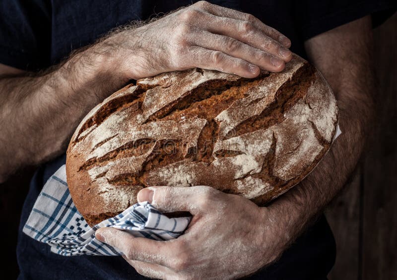 Homme de Baker tenant la miche de pain rustique dans des mains