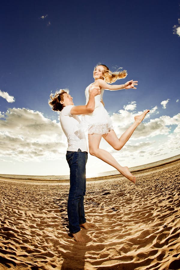 Happiness young men holding a women on the beach. Couples in love by a sea. Romantic date. Happiness young men holding a women on the beach. Couples in love by a sea. Romantic date.