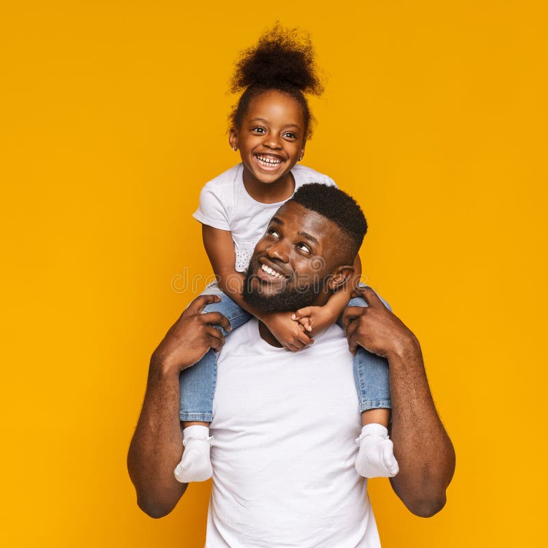Homme de couleur gai montant son mignon petite fille sur des épaules photos stock Homme de couleur gai montant son mignon petite fille sur des épaules photos stock