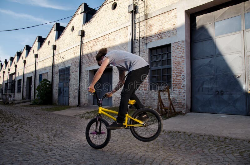 Homme de cycliste sautant avec le vélo de bmx sur la rue photo stock Homme de cycliste sautant avec le vélo de bmx sur la rue photo stock