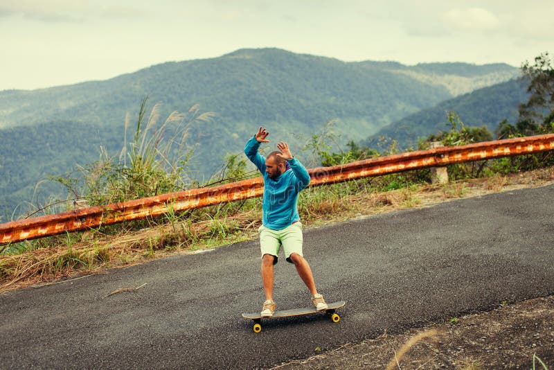 Homme de hippie longboarding extrêmement l'action dans des tropiques de route photos stock Homme de hippie longboarding extrêmement l'action dans des tropiques de route photos stock