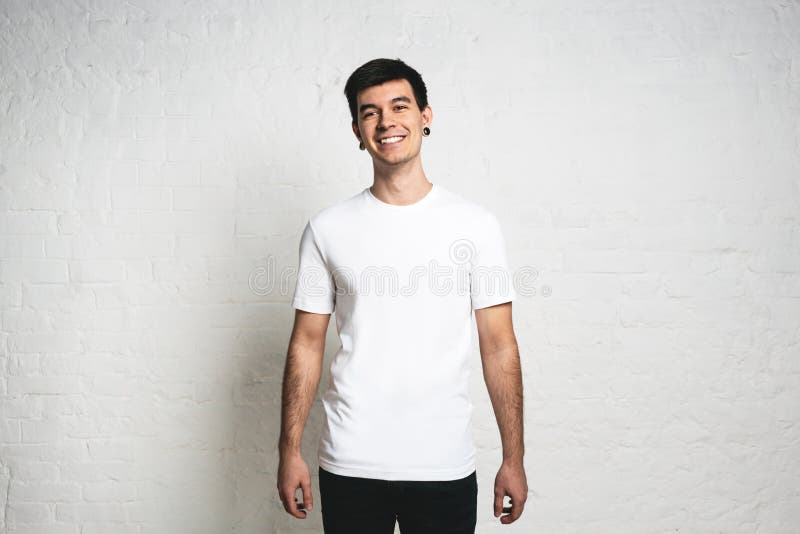 Homme de sourire dans le T-shirt vide blanc dans le studio Mur blanc photos stock Homme de sourire dans le T-shirt vide blanc dans le studio Mur blanc photos stock