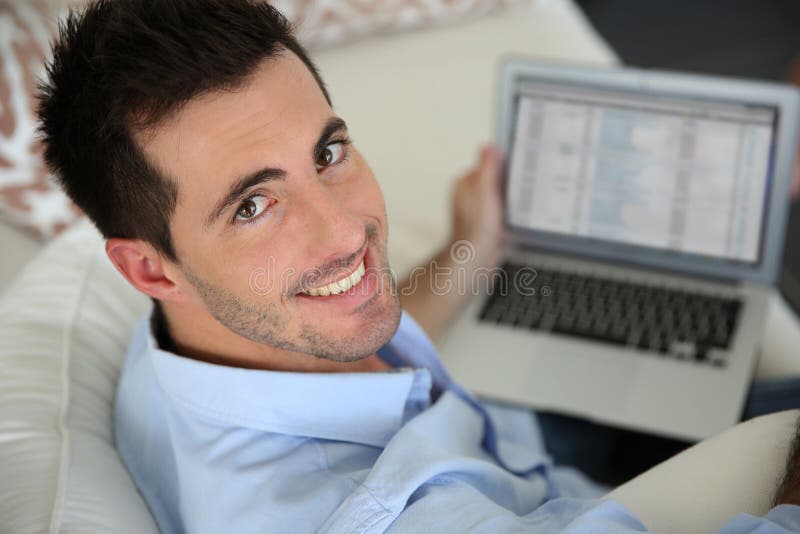 Homme de sourire à l'aide de l'ordinateur portable