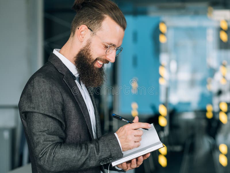 Homme de sourire écrivant l'ordre du jour quotidien d'affaires de planificateur photographie stock Homme de sourire écrivant l'ordre du jour quotidien d'affaires de planificateur photographie stock
