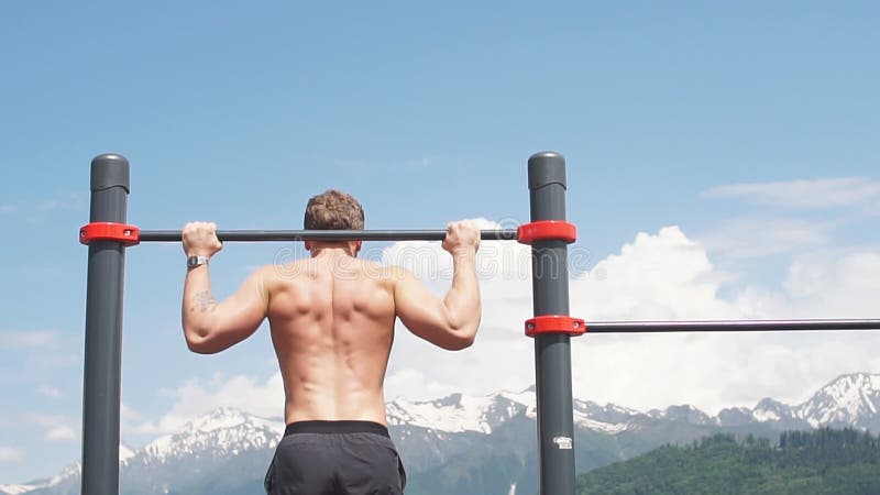 Homme de sports faisant l'exercice cabreur sur une barre horizontale contre un ciel bleu