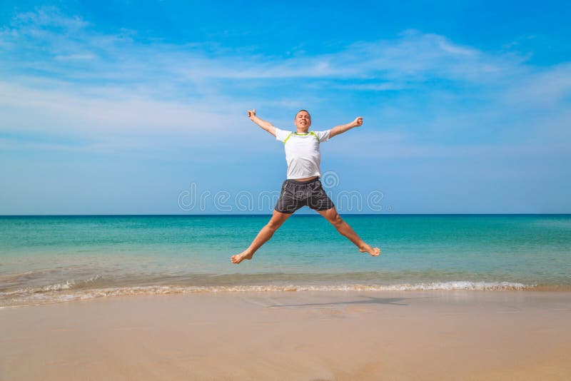 Homme de touristes heureux sautant dans une plage tropicale photo stock Homme de touristes heureux sautant dans une plage tropicale photo stock