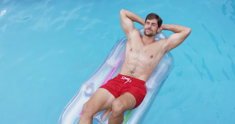 Homme détendant avec des mains derrière la tête sur le tube gonflable dans la piscine 4k banque de vidéos