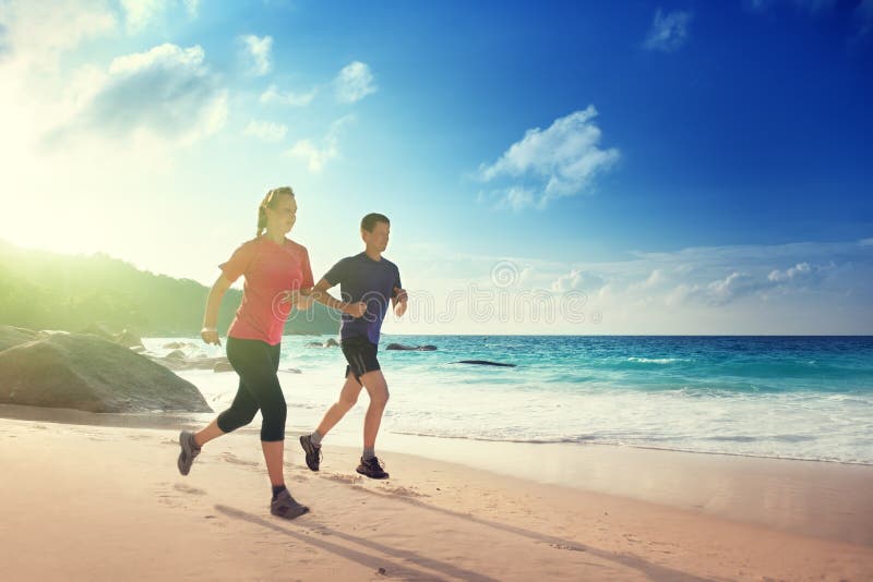 Homme et femme courant sur la plage tropicale photographie stock Homme et femme courant sur la plage tropicale photographie stock