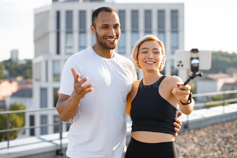 Homme et femme sportif écrivant un blog avec téléphone sur le toit. photos stock