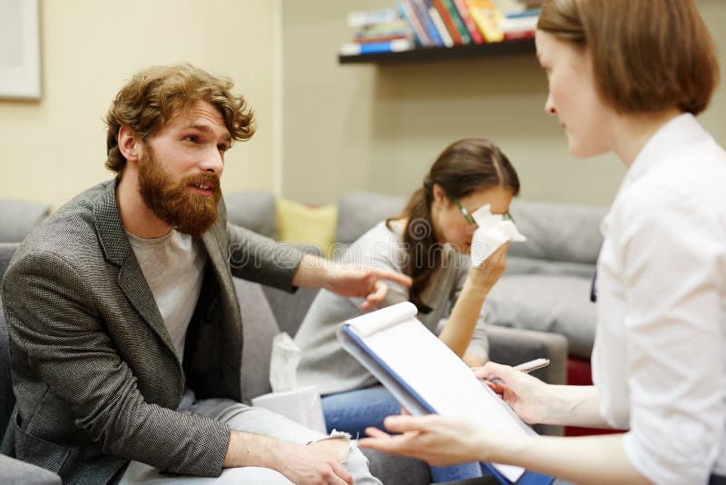 Homme fâché portant plainte au sujet de l'épouse au psychiatre image libre de droits Homme fâché portant plainte au sujet de l'épouse au psychiatre image libre de droits