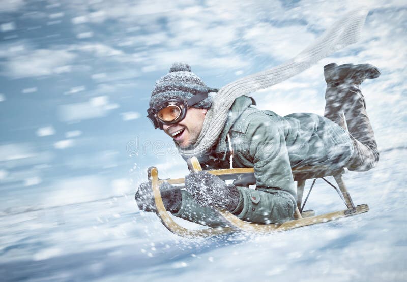 Homme gai sledding en bas d'une pente neigeuse dans à toute vitesse photos libres de droits Homme gai sledding en bas d'une pente neigeuse dans à toute vitesse photos libres de droits