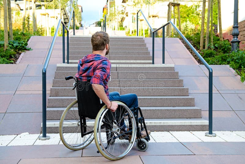 Homme handicapé dans le fauteuil roulant devant des escaliers