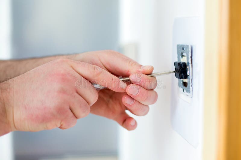 Homme installant l'interrupteur de lampe avec le tournevis photos libres de droits Homme installant l'interrupteur de lampe avec le tournevis photos libres de droits