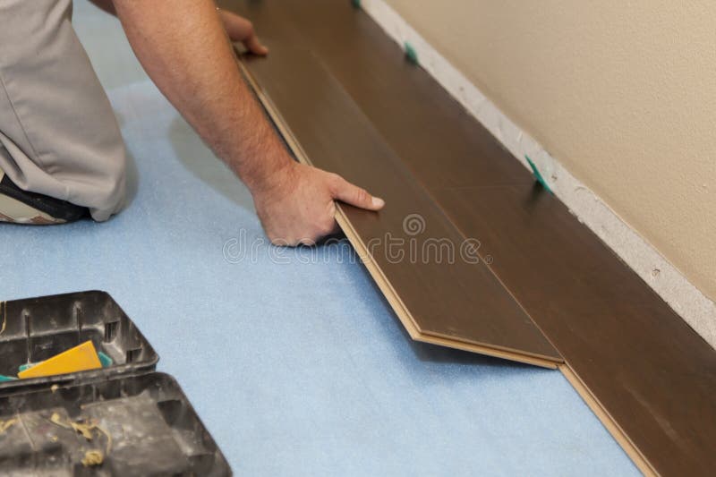 Homme installant le nouveau plancher en bois en stratifié photo stock Homme installant le nouveau plancher en bois en stratifié photo stock