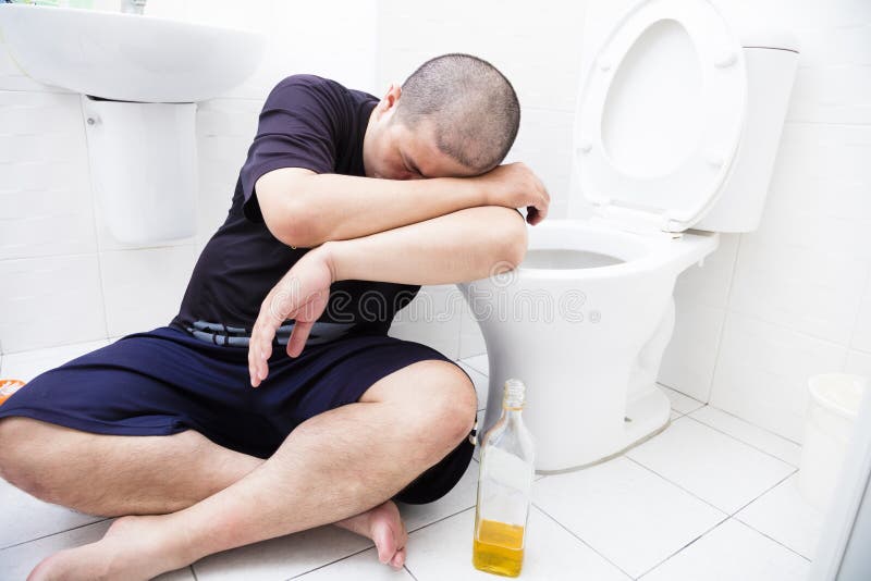 Homme ivre avec la bouteille de vin dans la toilette photos stock Homme ivre avec la bouteille de vin dans la toilette photos stock