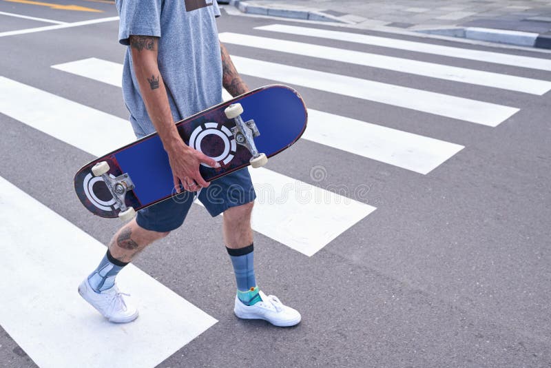 Homme jambes et marche avec skateboard en ville pour voyage de sport et aller pour le hobby. Patinage en plein air et mains photo libre de droits